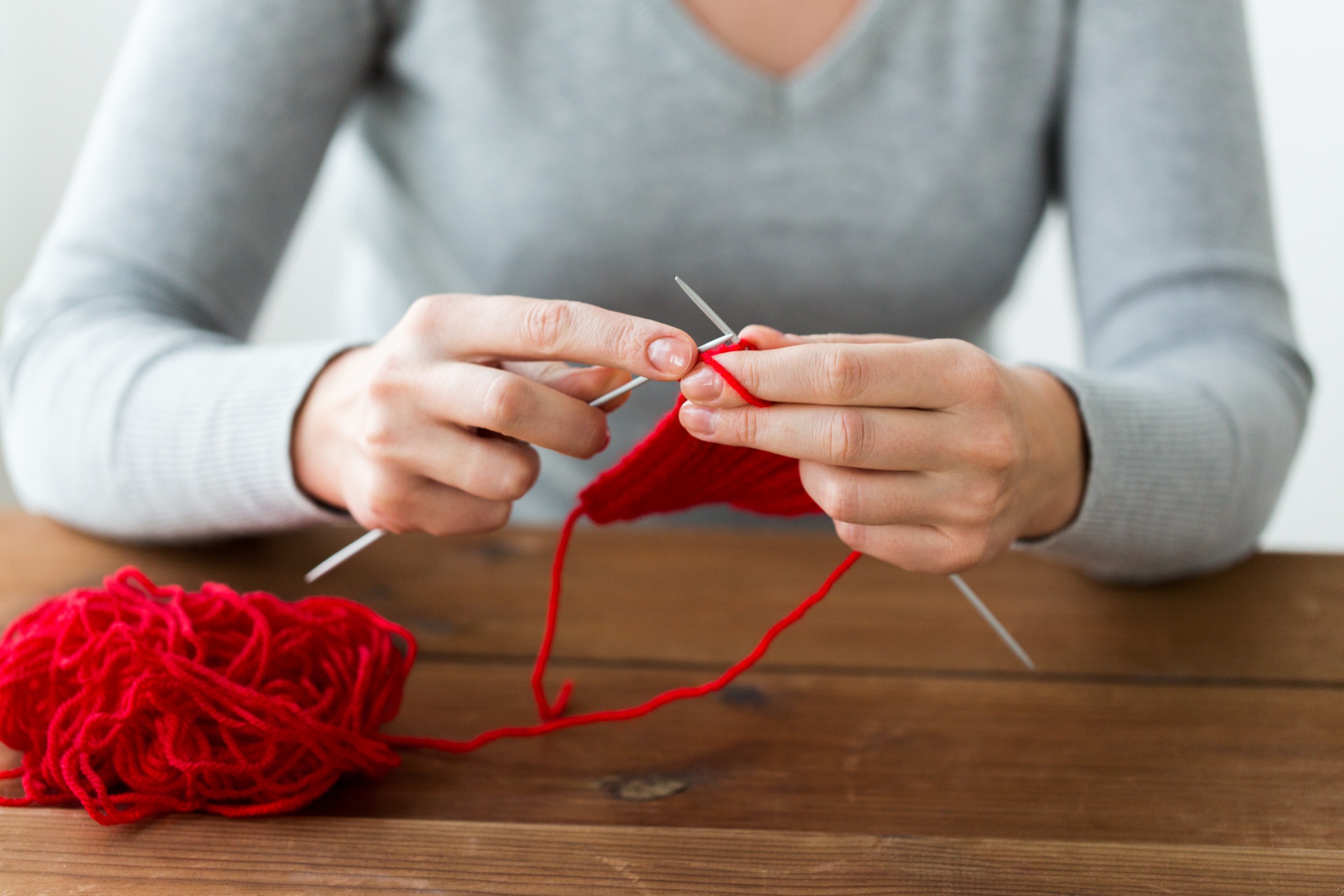 Woman knitting with needles and red yarn